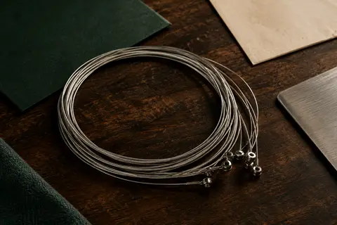 Cordes métalliques Elixir pour guitare électrique, enroulées sur un fond de bois sombre et de papier ivoire