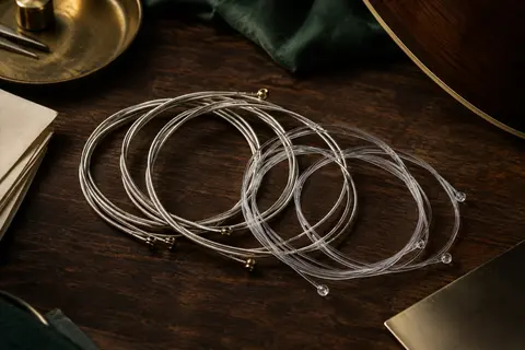 Jeu de cordes classiques avec aiguës en nylon transparent et basses filées argentées sur fond de bois sombre